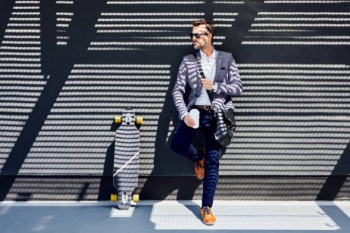 businessman with longboard and coffee leaning against wall - junk food stock pictures, royalty-free photos & images