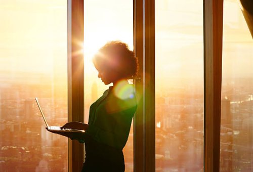 businesswoman on laptop at window in morning sun - hairstyle stock pictures, royalty-free photos & images