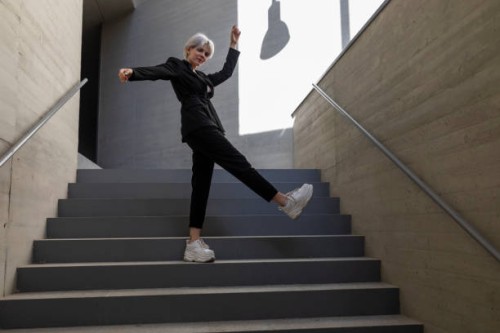 businesswoman wearing elegant suit dancing on steps in building - fashion stock pictures, royalty-free photos & images