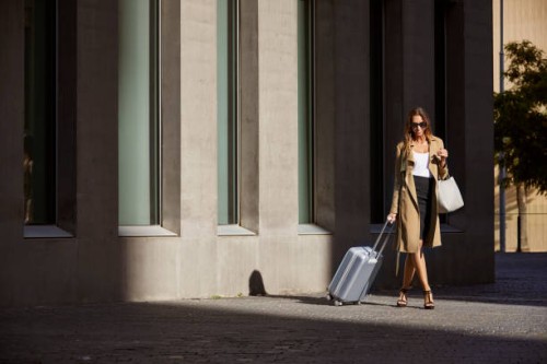 businesswoman with luggage walking outside airport - fashion stock pictures, royalty-free photos & images