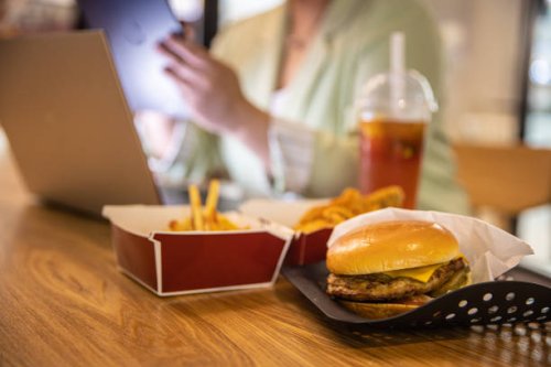 businesswoman working at laptop with fast food on restaurant table - junk food stock pictures, royalty-free photos & images