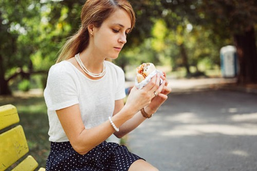 busy woman eating hamburger outside the office - junk food stock pictures, royalty-free photos & images