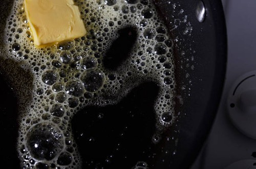 butter melting in pan - junk food stockfoto's en -beelden