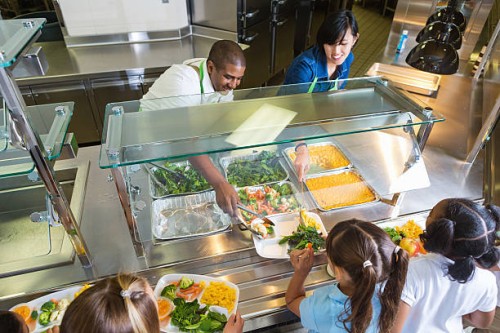 cafeteria worker serving trays of healthy food to children - food stock pictures, royalty-free photos & images