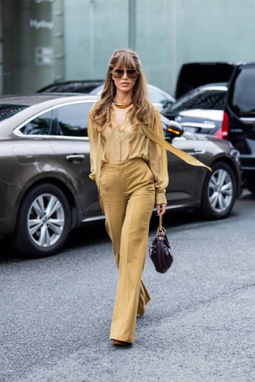 Camila Coelho wears golden necklace, ochre pants, blouse, burgundy bag outside Chloe during Womenswear Spring/Summer 2025 as part of Paris Fashion...