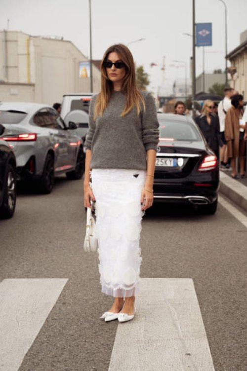 Camille Charriere wears a white top, laced skirt, pointed heels, and bag outside Prada during the Milan Fashion Week - Womenswear Spring/Summer 2024...