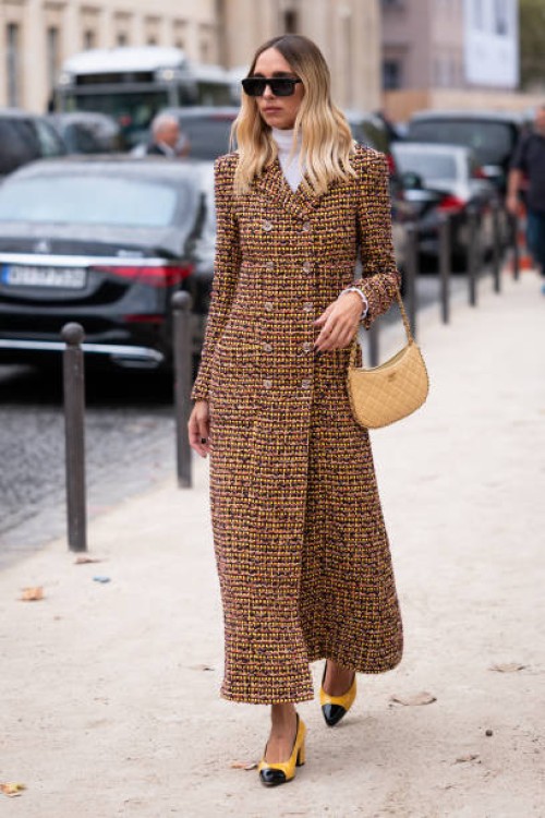 Candela Pelizza wears a yellow Chanel tweed coat, beige Chanel bag and yellow Chanel heels, outside Chanel, during the Womenswear Spring/Summer 2024...