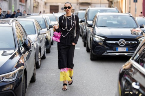 Candela Pelizza wears pink bag, black dress, pearl necklace outside Moschino during the Milan Fashion Week Womenswear Fall/Winter 2025/2026 on...
