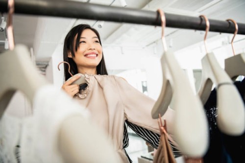 candid portrait of woman selecting clothing on rail - fashion stock pictures, royalty-free photos & images