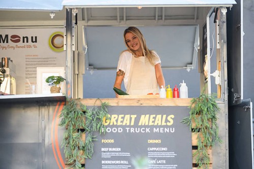 candid portrait of young woman working at food truck - junk food stock pictures, royalty-free photos & images