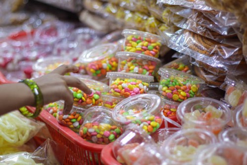candy store front with colorful candies and sugar coated fennel being picked up by a kid. - junk food stock pictures, royalty-free photos & images