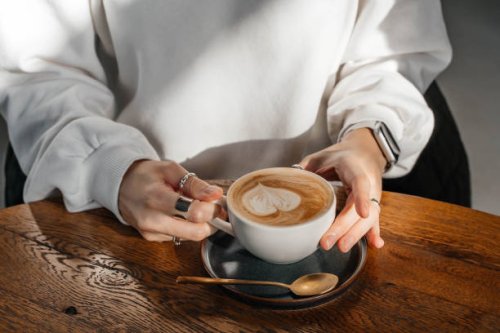 cappuccino in a white ceramic cup on a wooden table. close-up. - coffee stockfoto's en -beelden