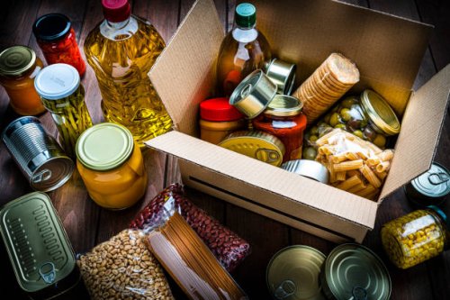 cardboard box filled with non-perishable foods on wooden table. high angle view. - food stock pictures, royalty-free photos & images