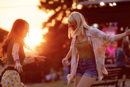 carefree female friends dancing during a music festival at sunset. - concert stock pictures, royalty-free photos & images