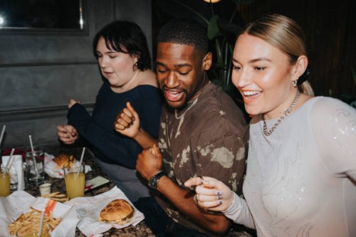 carefree male and female friends having fun while having snacks on table at nightclub - food stock pictures, royalty-free photos & images