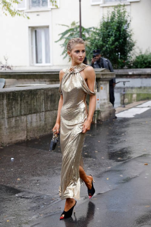 Caro Daur wears gold long dress, black Rabanne bag, black sandals, outside Rabanne, during Womenswear Spring/Summer 2025 as part of Paris Fashion...
