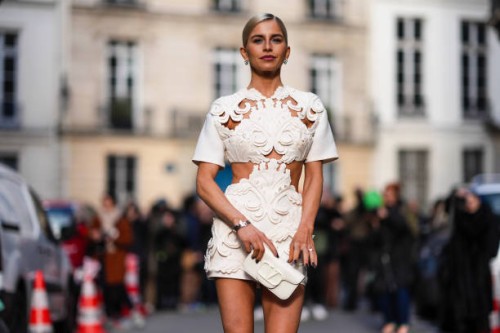 Caroline Daur wears a white ini dress with floral embroidery and cutouts and short sleeves, a leather bag from Valentino, outside Valentino, during...