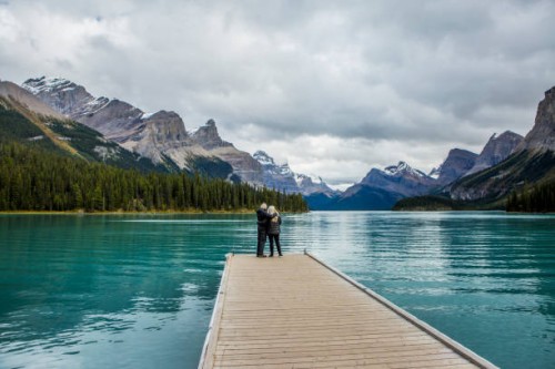caucasian couple standing at the end of dock on mountain lake - travel stock pictures, royalty-free photos & images