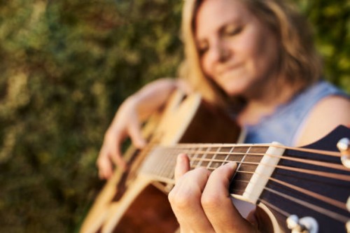 caucasian woman playing acoustic guitar in the garden. musical concept. - concert stock pictures, royalty-free photos & images