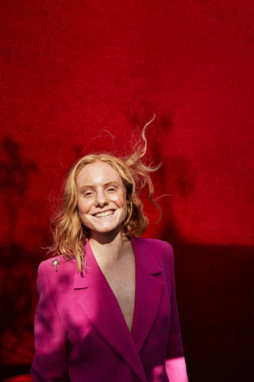 caucasian woman standing against red wall - fashion stock pictures, royalty-free photos & images