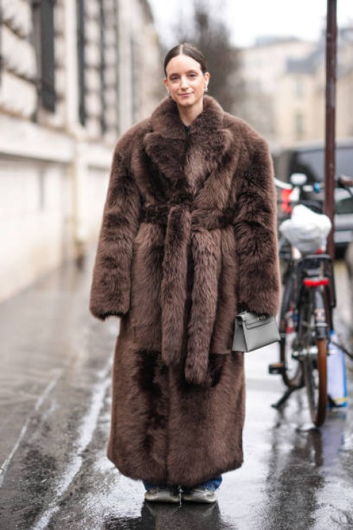Charlotte Groeneveld wears a brown oversized fluffy fur coat, a gray Hermes Kelly bag, outside Hermes, during the Womenswear Fall/Winter 2024/2025 as...