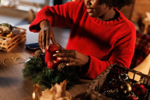charming young black woman decorating a christmas wreath - home decoration stock pictures, royalty-free photos & images