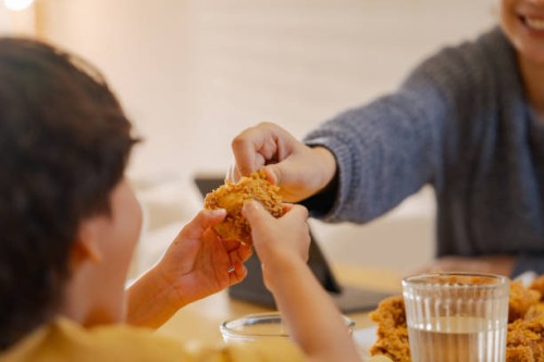 cheerful boy enjoying lunch break with his mother at home. - junk food stock pictures, royalty-free photos & images