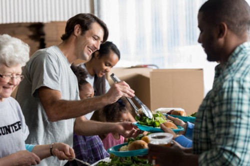 cheerful caucasian man serves healthy meal in soup kitchen - food stock pictures, royalty-free photos & images