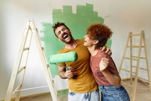 cheerful couple having fun while painting their new apartment in green. - home decoration stock pictures, royalty-free photos & images