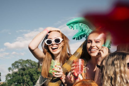 cheerful female friends enjoying drinks at music concert against sky in summer - concert stock pictures, royalty-free photos & images