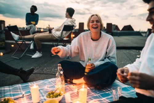 cheerful female with friends enjoying on building terrace during sunset - food stock pictures, royalty-free photos & images