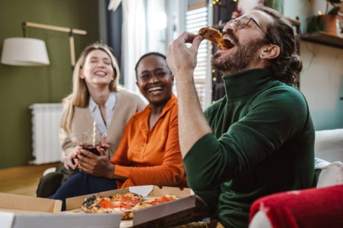 cheerful friends hanging out at home and eating pizza - junk food stock pictures, royalty-free photos & images