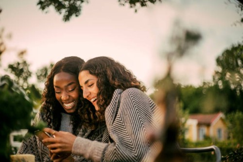 cheerful friends using phone in backyard during social gathering - garden decoration photos et images de collection