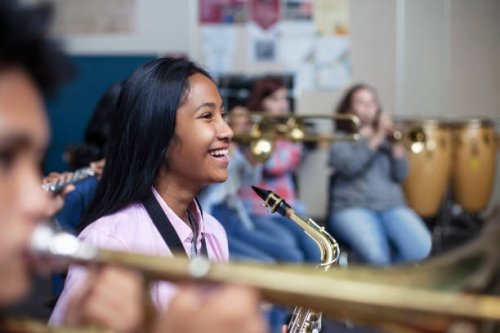 cheerful mixed ethnicity asian girl with saxophone in band orchestra class - concert stock pictures, royalty-free photos & images