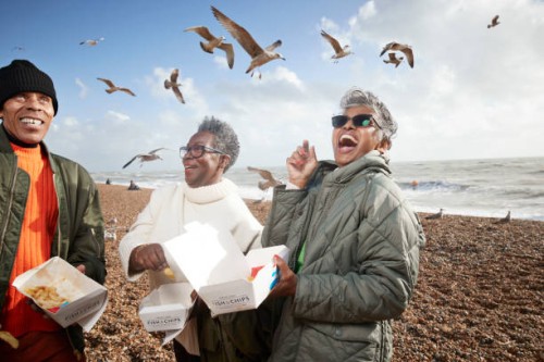 cheerful senior people with food containers at beach - junk food stock pictures, royalty-free photos & images