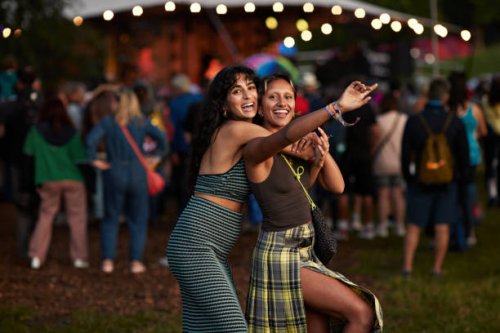 cheerful woman hugging female friend at concert - concert stock pictures, royalty-free photos & images