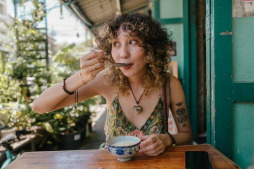 cheerful woman who sitting in front of restaurant enjoying eating tasty thai dessert. - food stock pictures, royalty-free photos & images