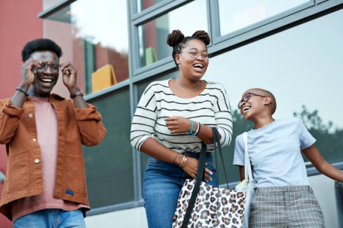 cheerful young friends against window at college - fashion stock pictures, royalty-free photos & images