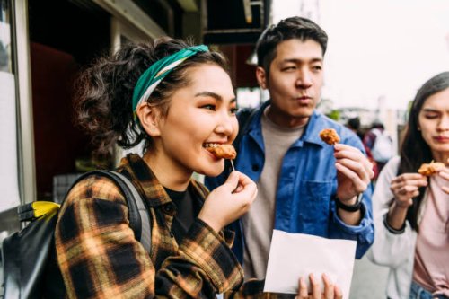 cheerful young woman eating street food with friends - food stock pictures, royalty-free photos & images