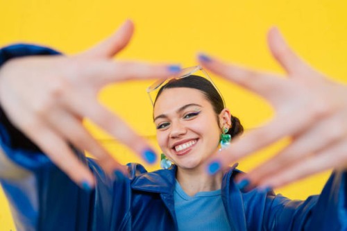cheerful young woman smiling, framing face with hands against bright yellow backdrop - fashion stock pictures, royalty-free photos & images