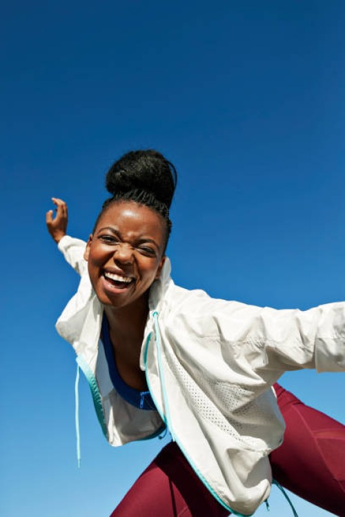 cheerful young woman with hair bun against clear sky during sunny day - fashion stock-fotos und bilder