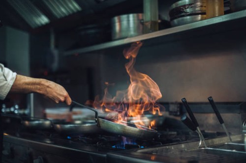 chef preparing a flambe dish at gas stove in restaurant kitchen - food stockfoto's en -beelden