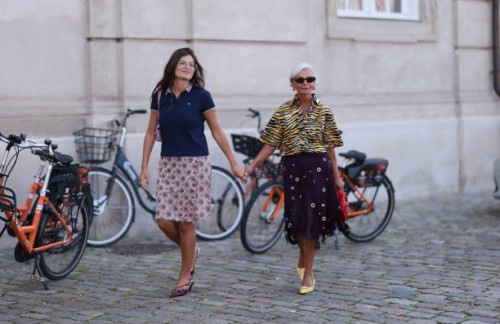 Cheyenne El-Khoury is seen wearing aviator glasses with a silver frame; a fine silver necklace with round pendant; a navy blue short-sleeved polo...