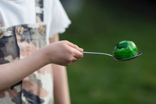 child (6-7) balancing a painted green easter egg on a spoon - garden decoration stock pictures, royalty-free photos & images
