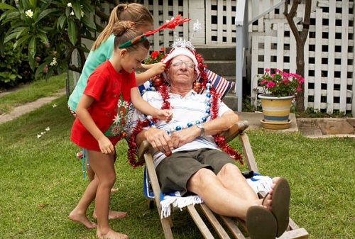 children (7-9) decorating senior man with christmas decorations in yard - garden decoration stock pictures, royalty-free photos & images