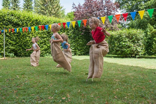 children having a sack race in garden on a birthday party - garden decoration stock pictures, royalty-free photos & images