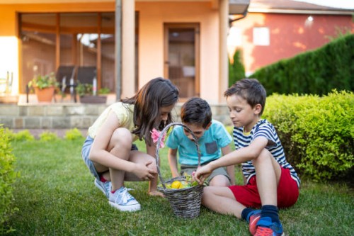 children sharing a basket of easter eggs in a garden - garden decoration stock pictures, royalty-free photos & images