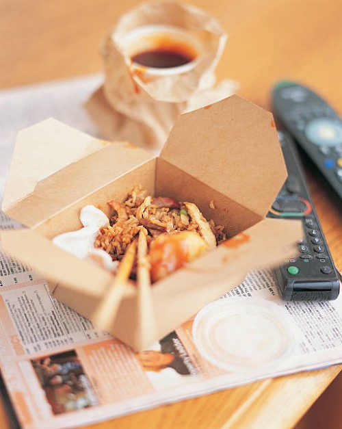 chinese meal in a carton by a remote control and a magazine - junk food stock pictures, royalty-free photos & images