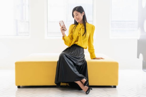 chinese woman on yellow bench with phone - fashion stock pictures, royalty-free photos & images