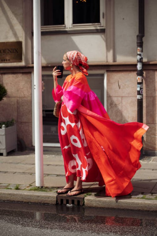 Chloe King wears white long dress with red flowers, orange and pink long coat and a head scarf outside the Gestuz show during day four of the...